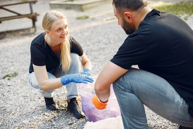 Pareja recoge basura en bolsas de basura en el parque