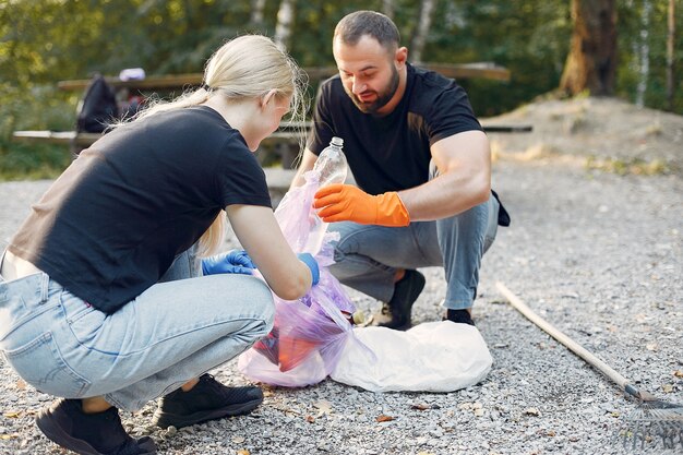 Pareja recoge basura en bolsas de basura en el parque