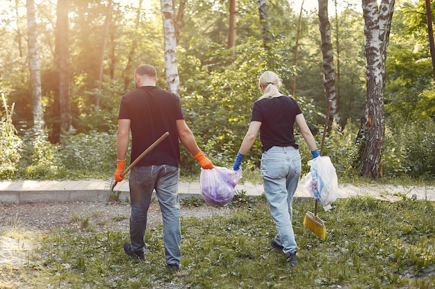 Pareja recoge basura en bolsas de basura en el parque