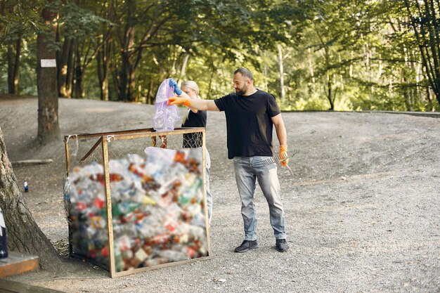 Foto gratuita pareja recoge basura en bolsas de basura en el parque