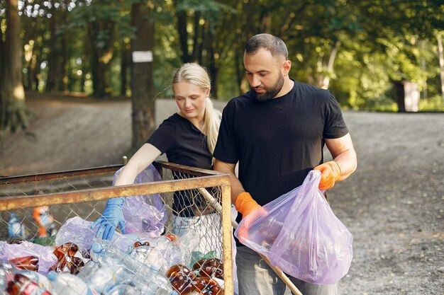 Pareja recoge basura en bolsas de basura en el parque