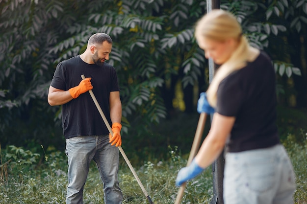 Foto gratuita pareja recoge hojas y limpia el parque