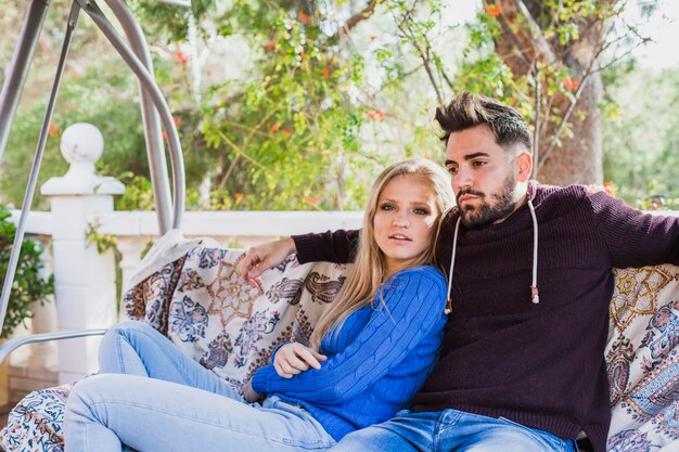 Pareja de refrigeración en el sofá de oscilación en la terraza