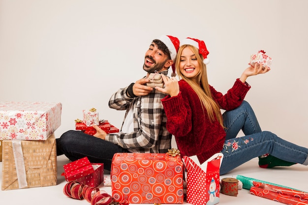 Foto gratuita pareja con regalos apoyados uno contra el otro