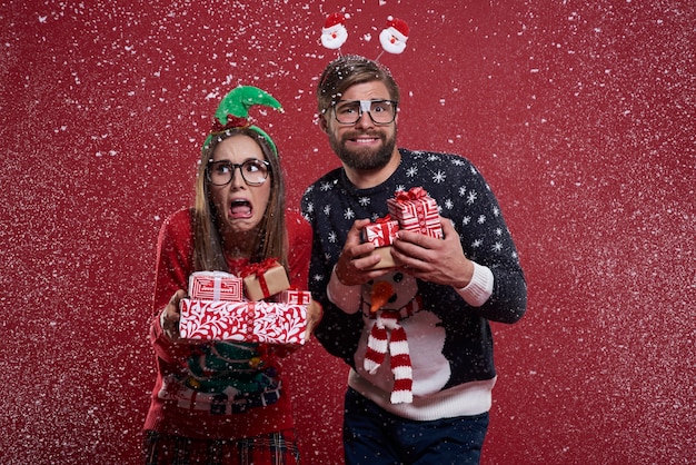 Pareja con regalos de pie en la nieve.