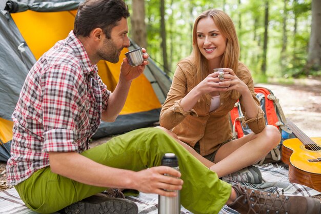 Pareja relajada disfrutando en el bosque y tomando café