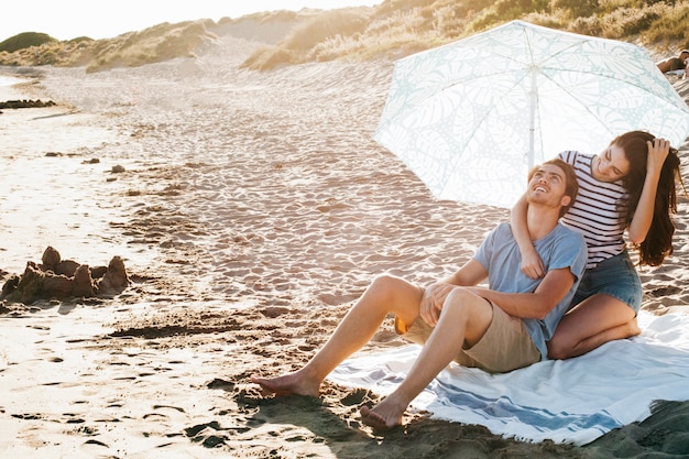 Foto gratuita pareja relajando en toalla por la playa