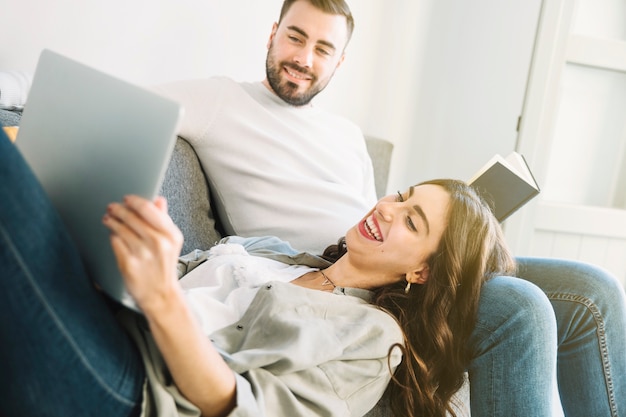 Pareja relajante con ordenador portátil y libro