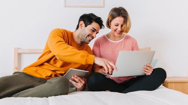 Foto gratuito una pareja riendo usando una computadora portátil en la cama