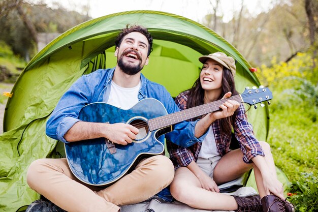 Pareja de risa tocando la guitarra