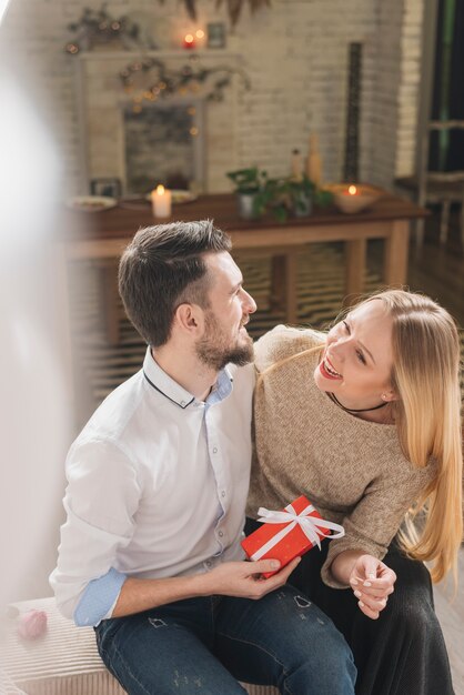 Pareja risueña con pequeño regalo.