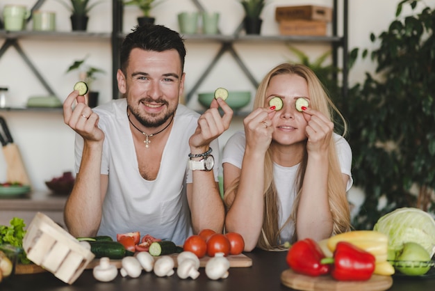 Foto gratuita pareja con rodajas de pepino detrás del mostrador de la cocina