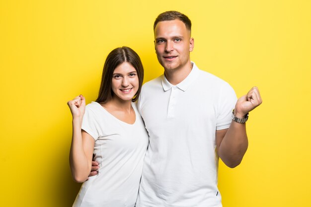 Pareja romántica aislada sobre fondo amarillo abrazándose juntos vestidos con camisetas blancas