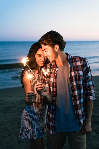 Pareja romántica con bengala en la playa