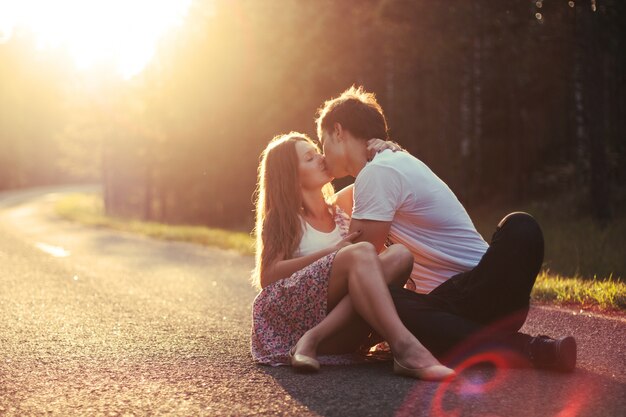 Pareja romántica besándose en la carretera al atardecer