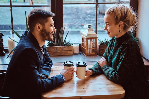 Una pareja romántica en el café está tomando café y hablando. Hombre guapo y hermosa chica disfrutando de estar juntos.