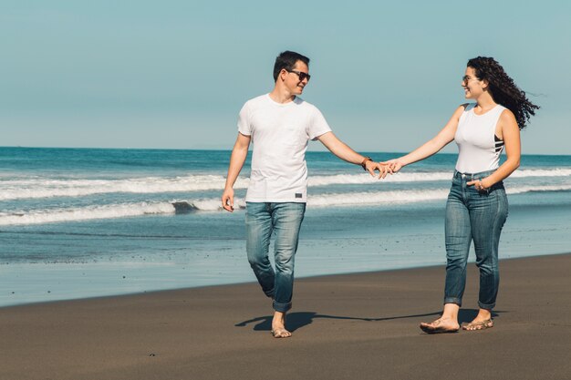 Pareja romántica caminando en la playa soleada