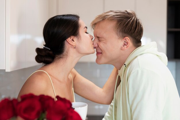 Pareja romántica en casa celebrando el día de San Valentín con ramo de hermosas rosas rojas