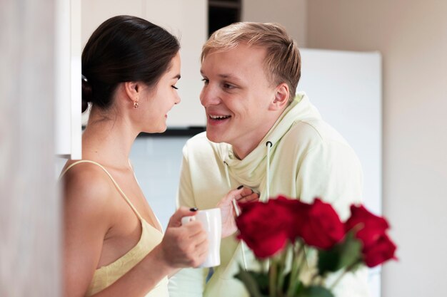 Pareja romántica en casa celebrando el día de San Valentín con ramo de hermosas rosas rojas