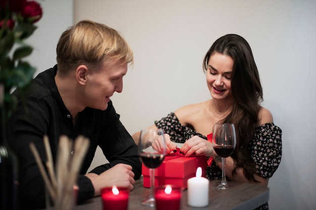 Pareja romántica celebrando el día de San Valentín en casa con vino y presente