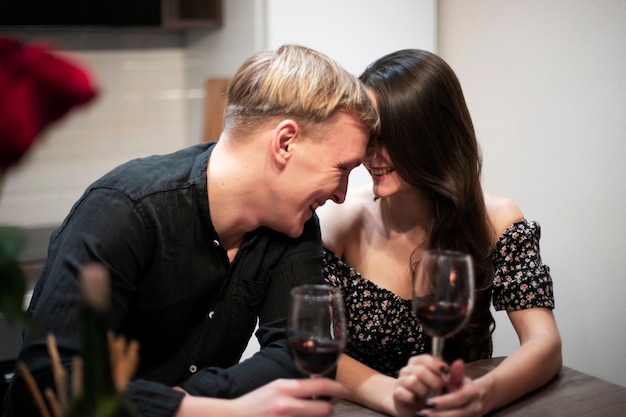 Pareja romántica celebrando el día de San Valentín en casa con vino