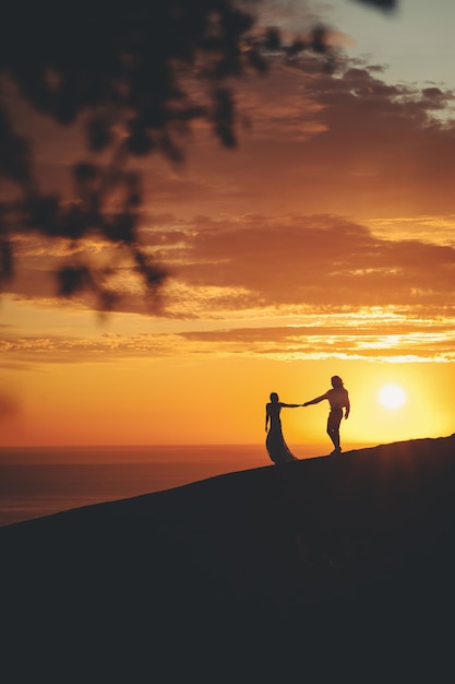 Pareja romántica cogidos de la mano en la orilla del mar durante la puesta de sol