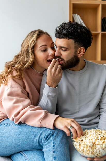 Pareja romántica comiendo palomitas de maíz en casa