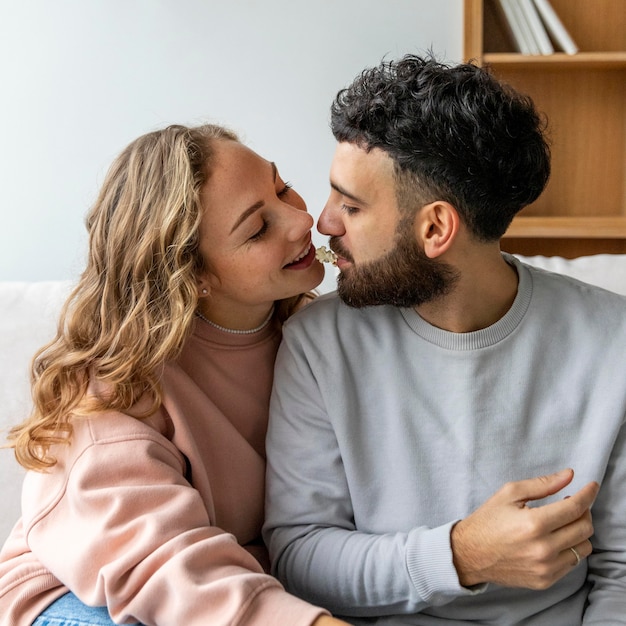 Pareja romántica comiendo palomitas de maíz mientras se besa en casa