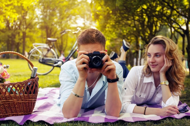 Pareja romántica haciendo fotos en tiempo de picnic en un parque.