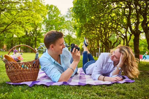Pareja romántica haciendo fotos en tiempo de picnic en un parque.