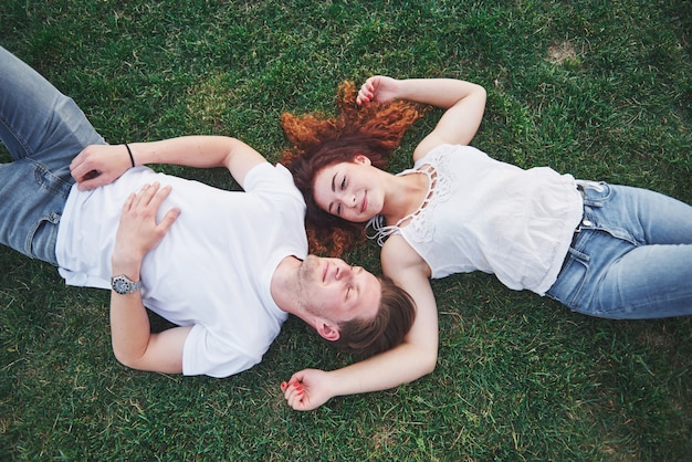 Pareja romántica de jóvenes tirado en el pasto en el parque.