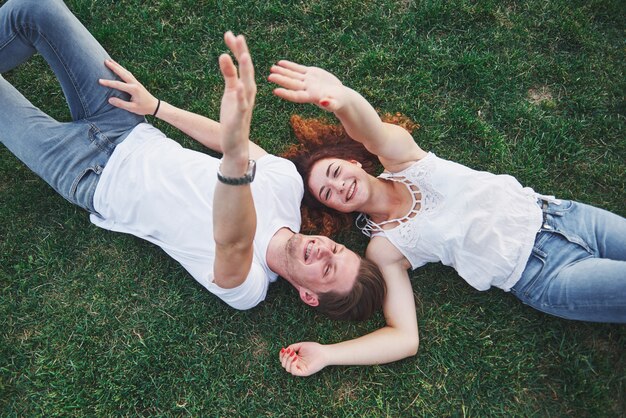 Pareja romántica de jóvenes tirado en el pasto en el parque.