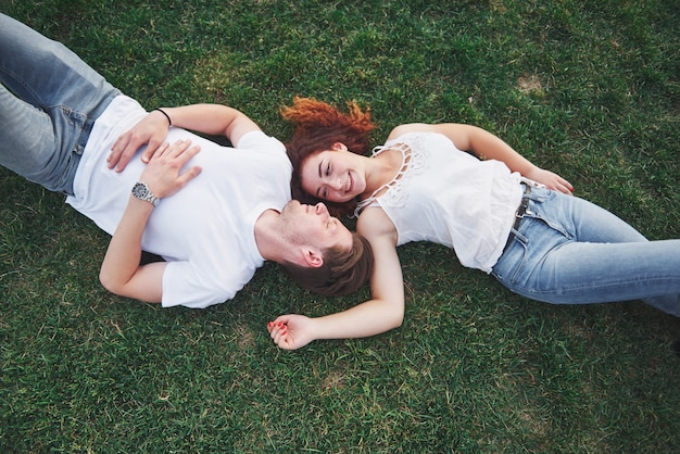 Pareja romántica de jóvenes tirado en el pasto en el parque.