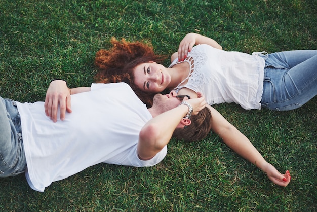 Pareja romántica de jóvenes tirado en el pasto en el parque.