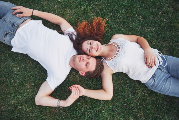 Pareja romántica de jóvenes tirado en el pasto en el parque.