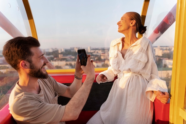 Foto gratuita pareja romántica juntos en la rueda de la fortuna en el parque