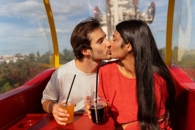 Foto gratuita pareja romántica juntos en la rueda de la fortuna en el parque