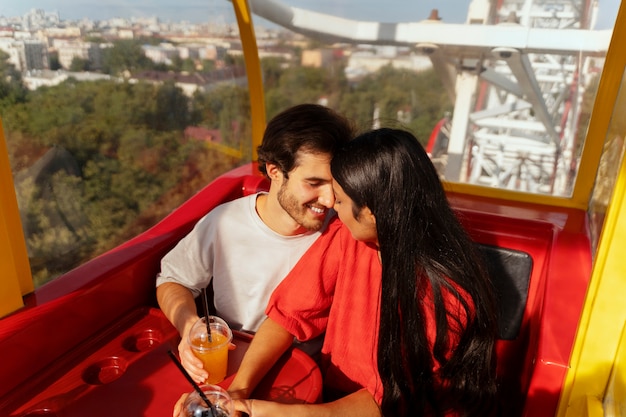 Pareja romántica juntos en la rueda de la fortuna en el parque