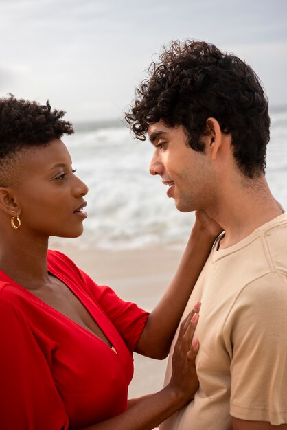 Pareja romántica mostrando afecto en la playa cerca del océano