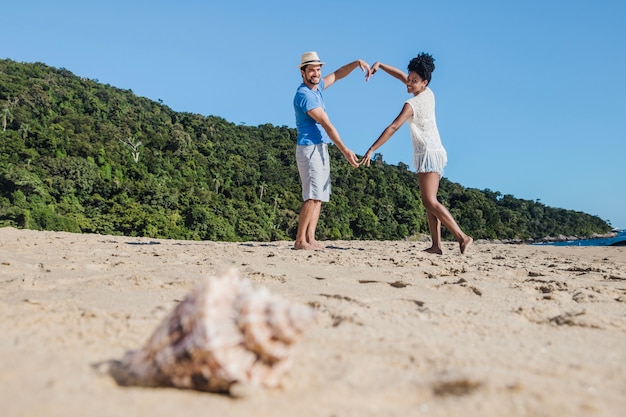 Pareja romántica en la playa con concha en primer plano