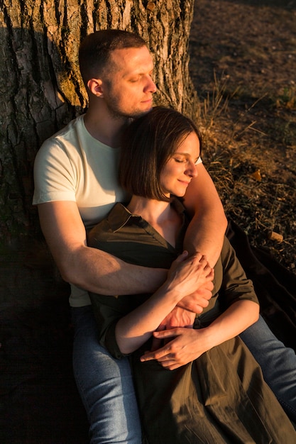 Pareja romántica sentada cerca del árbol