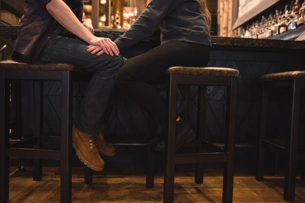 Pareja romántica sentada en un taburete en la barra de bar