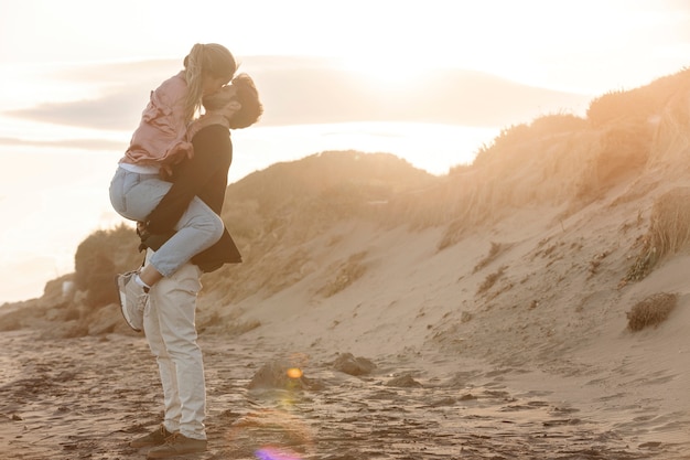 Pareja romántica de tiro completo besándose en la playa