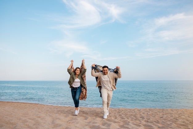 Foto gratuita pareja romántica de tiro completo con manta a cuadros