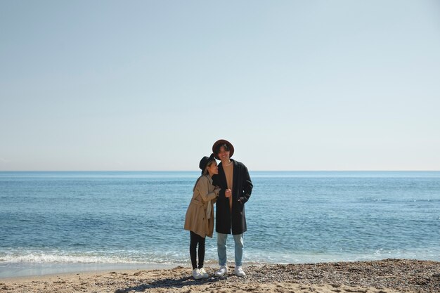 Foto gratuita pareja romántica de tiro completo en la playa