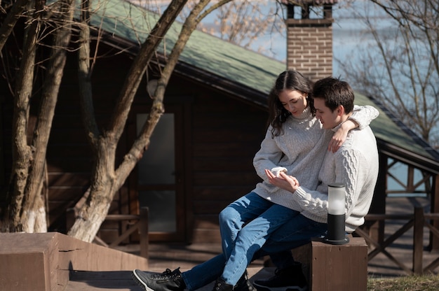 Pareja romántica de tiro completo sentada al aire libre