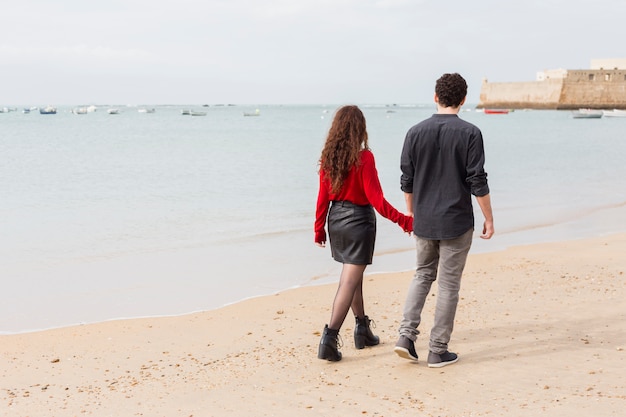 Foto gratuita pareja en ropa casual caminando en la orilla del mar