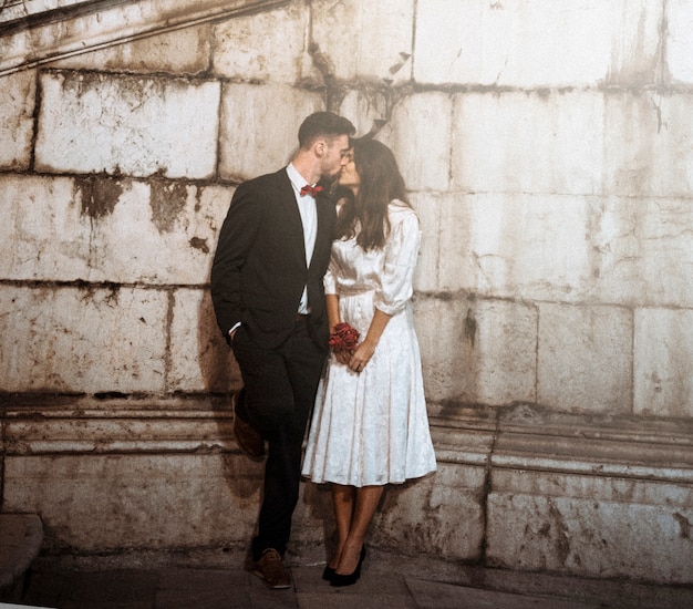 Pareja en ropa elegante besándose en la calle de noche