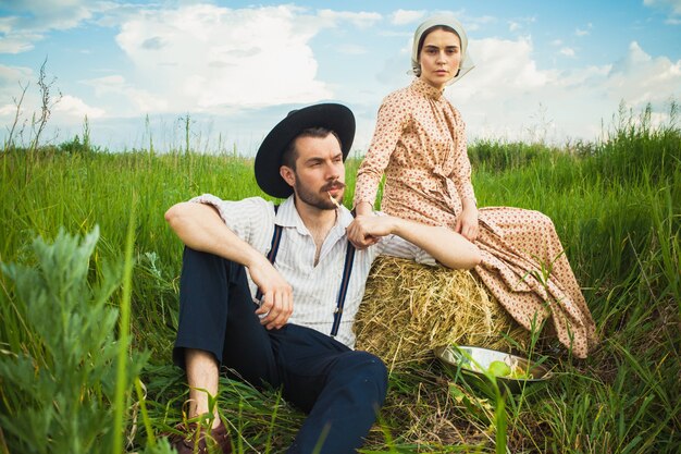 Pareja en ropa rural sentada en el campo