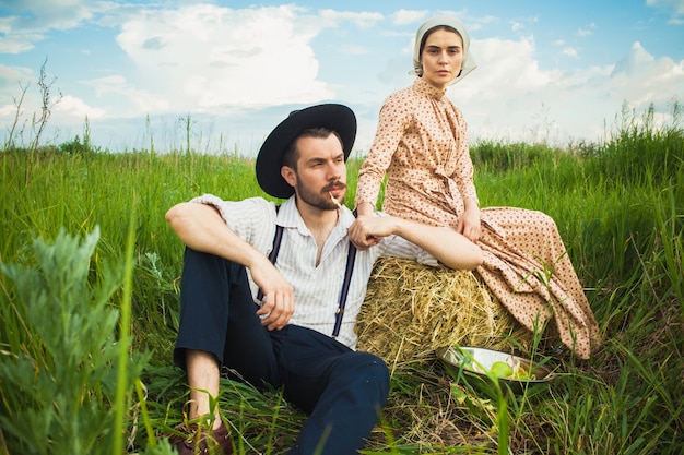 Pareja en ropa rural sentada en el campo